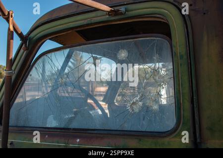 Le verre cassé de la vitre latérale gauche d'un vieux camion vert. Banque D'Images