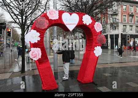 Dublin, Irlande - 14 février 2025 - une arche en forme de cœur décorée d'images de roses rouges et roses, située sur O'Connell Street lors d'une Saint Valentin humide dans la ville de Dublin Banque D'Images