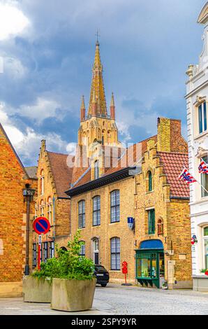 Quartier de la vieille ville de Bruges, rue étroite, maisons traditionnelles avec murs de briques dans le centre historique de la ville de Bruges, église catholique de notre-Dame avec Banque D'Images