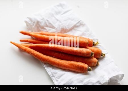 Bouquet de carottes sont sur un chiffon blanc. Les carottes sont longues et minces. Ils sont tous de tailles différentes Banque D'Images