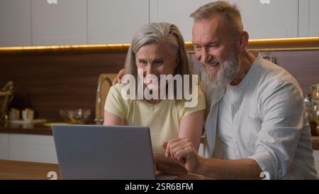 Famille heureuse vieux couple aîné utilisant un ordinateur portable commandant la livraison de nourriture dans le supermarché Internet e-commerce domestique femme moyenne de magasin en ligne d'épicerie Banque D'Images