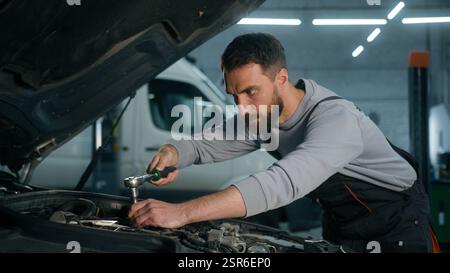 Ingénieur mécanicien automobile professionnel homme caucasien travaillant dans le spécialiste du moteur de service de véhicule fixant l'automobile à moteur à l'aide de l'outil de clé à clé Banque D'Images