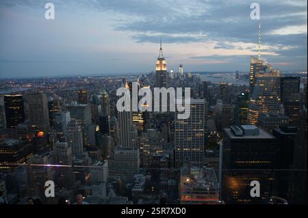 Vue aérienne de New York au crépuscule. Gratte-ciel illuminés contre un ciel dramatique. Symbole emblématique du capitalisme américain et de la résilience. Un intemporel Banque D'Images