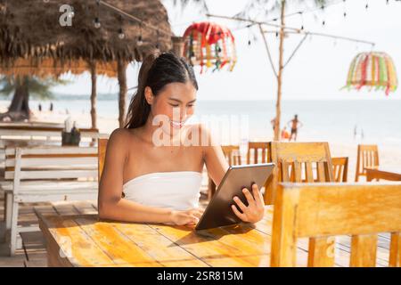Jeune femme asiatique utilisant un ordinateur tablette sur la plage Banque D'Images