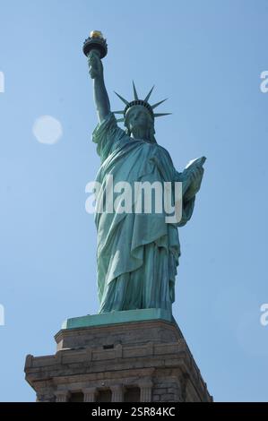 Une vue majestueuse sur la Statue de la liberté se dresse sur Liberty Island dans le port de New York, baignée par la lumière d'un temps clair. Ce symbole emblématique de f Banque D'Images