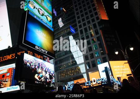 Les touristes à New York, Times Square à Manhattan bourdonnent d'activité sous une couverture de lumières nocturnes. Les publicités Sony et Reuters viennent s'ajouter à la vibr Banque D'Images