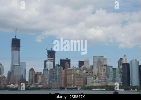 À New York, Manhattan, un ferry traverse l'eau au coucher du soleil, offrant une vue imprenable sur les gratte-ciel de la ville. La lumière chaude peint le skyscrap Banque D'Images