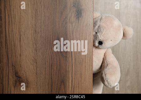 Ours en peluche mignon jetant un coup d'œil hors de la planche de bois. Espace pour le texte Banque D'Images