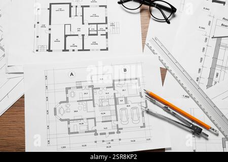 Différents dessins architecturaux, crayon, règle, verres et séparateur sur table en bois, pose à plat Banque D'Images