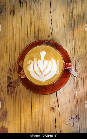 Cappuccino avec motif floral en mousse de lait, table en bois, café, tasse, tasse à café, boisson, caféine gastronomie Banque D'Images
