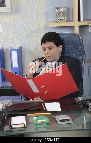 Exécutif assis dans la cabine ouvrir le dossier rouge à la main pensant avec tenir le crayon et toucher aux lèvres MR # 687U Banque D'Images