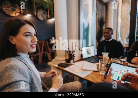Équipe multiraciale discutant des stratégies d'affaires lors d'une réunion dans un café moderne Banque D'Images