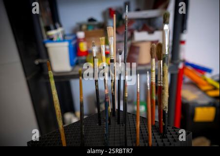 Plusieurs pinceaux réunis, différentes tailles avec des signes d'usure et des taches de peinture, scène d'un atelier artistique. Banque D'Images
