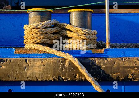 Corde épaisse enroulée autour de bornes bleues sur un quai altéré. Colindres, cantabrie, espagne Banque D'Images