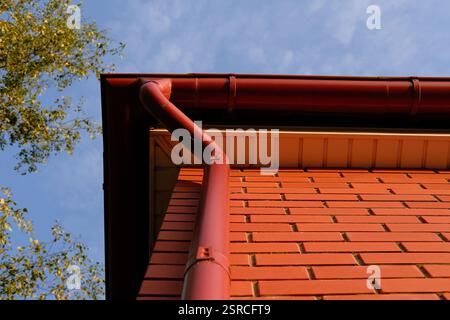 Gouttière de pluie du toit de la maison en briques rouges. Système de gouttière métallique. Conduite d'eau de pluie. Banque D'Images