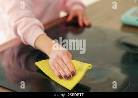 une fille en gants de caoutchouc jaunes lave une cuisinière électrique Banque D'Images