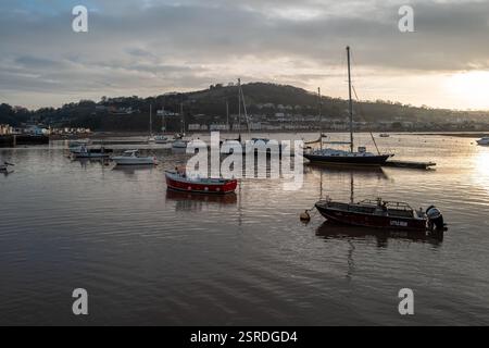 Bateaux amarrés et propriétés côté plage sur le bord de la rivière Teign au coucher du soleil. Village de Shaldon en arrière-plan. Quay au premier plan. Devon Angleterre. Banque D'Images