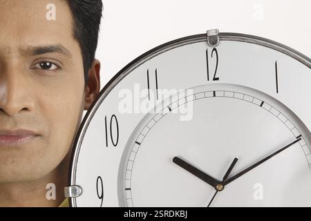Businessman holding wall clock dans une main son côté gauche du visage MR# 703T Banque D'Images