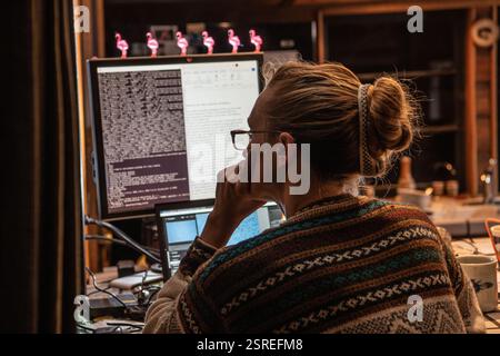 Une femme programmant et exécutant du code travaillant tard à la maison. Banque D'Images