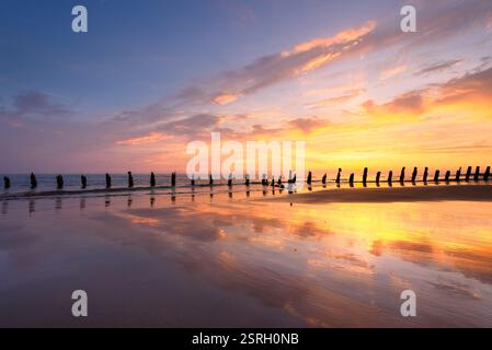 Vieux groynes de défense maritime utilisés pour protéger les côtes de l'érosion au coucher du soleil. Walney, Lake District, Royaume-Uni. Banque D'Images