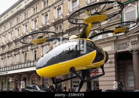 Un drone taxi autonome jaune et noir, exposé devant la gare de Charing Cross à Londres, Royaume-Uni. Le modèle met en valeur le transport futur. Banque D'Images