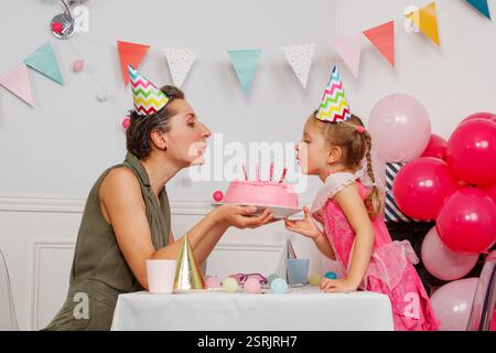 Mère avec fille souffler des bougies sur le gâteau de fête d'anniversaire Banque D'Images