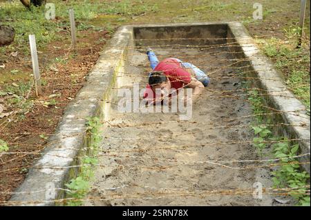 Homme rampant sous le fil barbelé, Raigad, Maharashtra, Inde, Asie, MR#364, Asie Banque D'Images