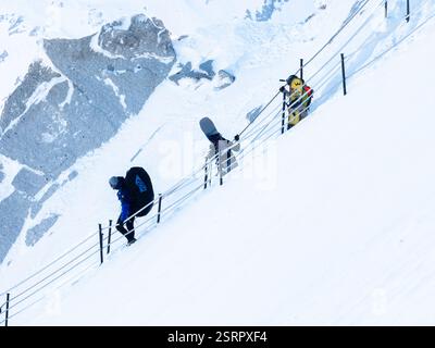 Chamonix-Mont-Blanc, France, 21 janvier 2025. Les personnes en parapente avec des sacs à dos et un parachute à l'intérieur descendent la pente abrupte et enneigée de l'A Banque D'Images