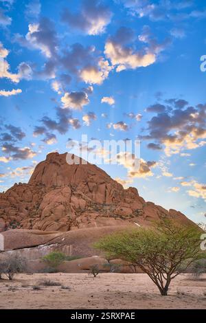 Petite montagne Spitzkoppe et quelques nuages en contre-jour du lever du soleil, Namibie, Afrique. Banque D'Images