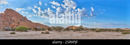 Petite montagne Spitzkoppe avec cabines de camping en contre-jour du lever du soleil, une vue sur le désert au sud, Namibie, Afrique. Banque D'Images