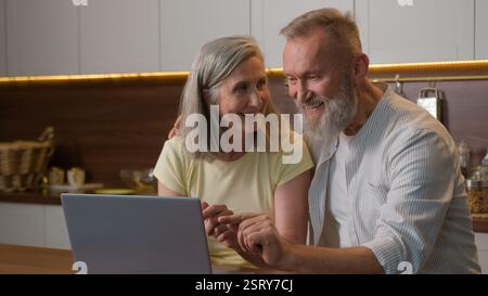 Famille heureuse vieux couple aîné utilisant un ordinateur portable commandant la livraison de nourriture dans le supermarché Internet e-commerce domestique femme moyenne de magasin en ligne d'épicerie Banque D'Images