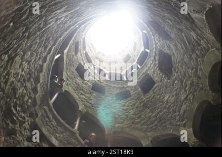 Sintra, Portugal. Un escalier en pierre sinueux descend en spirale, disparaissant dans un puits profond. Cette descente énigmatique évoque le passage de la vie dans un Banque D'Images
