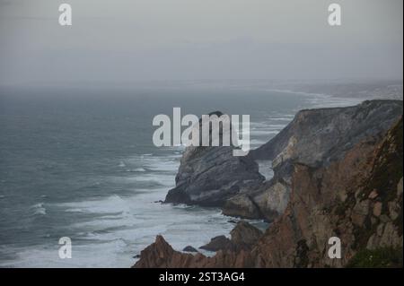 Falaises accidentées, vagues de l'Atlantique s'écrasent contre le bord du Portugal. Le point le plus à l'ouest de l'Europe, un paysage marin spectaculaire. Palais de Pena, Sintra, Portugal. Un conte de fées Banque D'Images