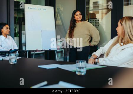 Une étudiante universitaire de troisième cycle engage ses pairs avec une présentation de mode créative dans une salle de séminaire académique. Banque D'Images
