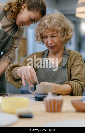 Femme senior dans le tablier forme de l'argile à la classe de céramique engagée dans l'activité artistique Banque D'Images