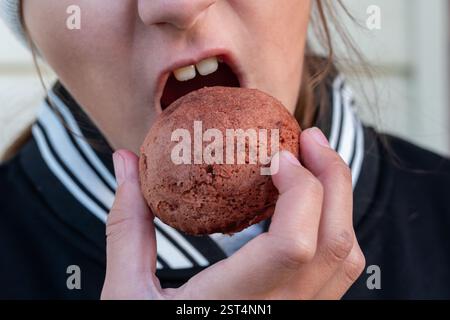 Fille mangeant du Donut sucré. Fille mangeant du gâteau en hiver, Portrait de belle fille avec beignet chocolat. Banque D'Images