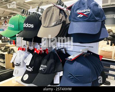 Lviv, Ukraine - 16 février 2025 : différentes casquettes de marque, y compris Adidas et Puma, disposées soigneusement sur un présentoir de magasin. Banque D'Images
