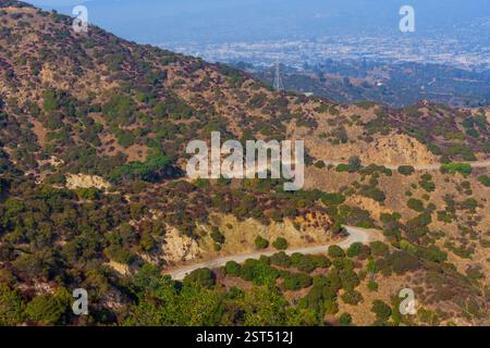 Vue aérienne des sentiers sinueux entourés de verdure dans Griffith Park, Californie, surplombant le paysage lointain et la ville. Banque D'Images
