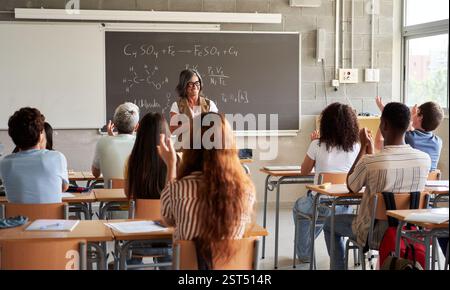 Enseignante d'âge mûr expliquant les formules de chimie aux élèves du secondaire. Banque D'Images