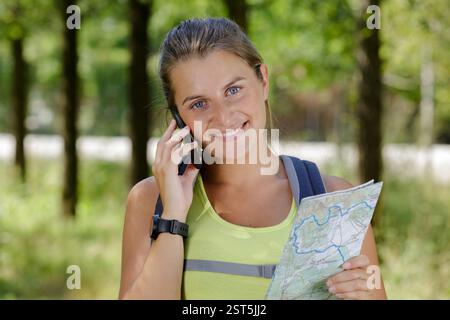 femme randonneurs regardant la carte tout en utilisant le téléphone Banque D'Images