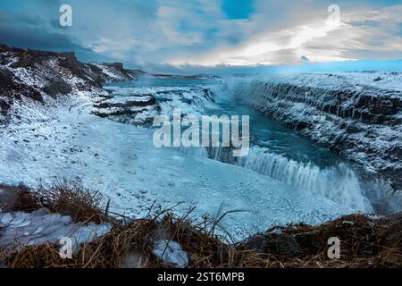 Cascade Gullfoss en Islande. Une puissante cascade glaciaire affichant des tons bleus glacés contre des falaises enneigées de chaque côté. Banque D'Images