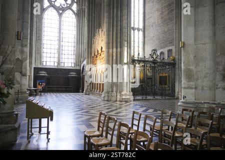 Une chapelle latérale sereine dans la cathédrale, avec de grands vitraux, des sculptures complexes en pierre, des portes en fer forgé et des chaises en bois. Amiens. France 17.02.2025 Banque D'Images