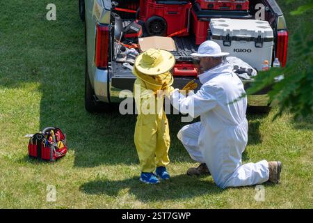 Un apiculteur et son fils ont revêtu des vêtements de protection avant de retirer une colonie d'abeilles d'une maison. Banque D'Images