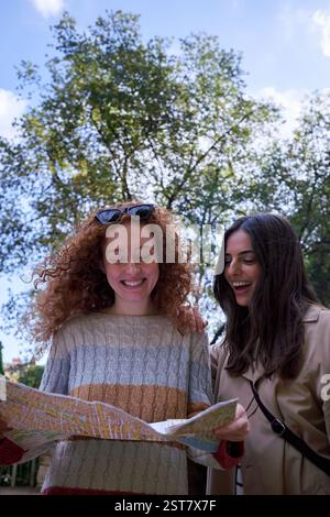 Deux touristes femmes heureuses voyageant, en utilisant une carte papier à la recherche de la direction. Banque D'Images