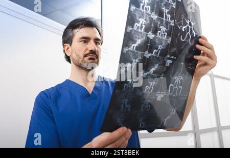 Angiographie par résonance magnétique. Le médecin en gommage bleu examine attentivement une série de films d'imagerie IRM montrant les artères, en se concentrant sur la va du patient Banque D'Images