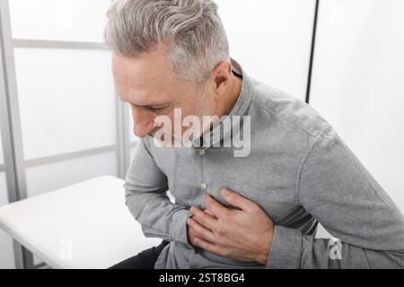 Traitement des maladies cardiaques. L'homme mature ressent une douleur thoracique dans un cadre clinique lors d'une visite chez un cardiologue pour des problèmes de santé et des douleurs cardiaques Banque D'Images