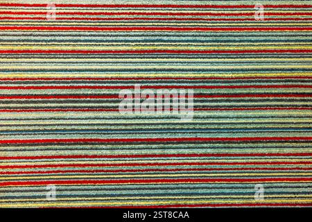 Vue rapprochée du tapis rayé avec motif coloré texturé avec des lignes horizontales rouges, jaunes, bleues et vertes. Banque D'Images
