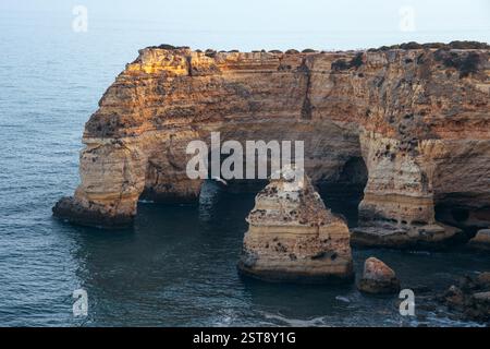 Falaises, formations rocheuses et arches naturelles sur la plage de la Marina au coucher du soleil dans la région de l'Algarve près des villes d'Albufeira et Portimao. Portugal. Banque D'Images
