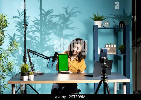 Ingénieur technique présentant une tablette à écran isolé dans une gamme de prix d'entrée de gamme à petit budget, filmant depuis un home studio faiblement éclairé. Créateur de contenu examinant la maquette d'un appareil numérique devant le public en ligne Banque D'Images