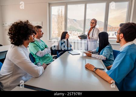 Une équipe médicale de médecins discutant lors d'une réunion dans la salle de conférence en utilisant la technologie moderne. Banque D'Images